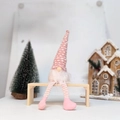 Roze gestreepte gebreide kerstkabouter met lange benen en roze schoenen op een kruk - Roze