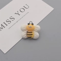 Macro shot of a yellow and white resin bee charm with a metal ring for DIY jewelry making - Bee