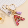 Macro detail of resin letter A keychain with colorful sequins and purple tassel - Letter A