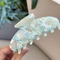 Primo piano di un fermaglio per capelli in acetato marmorizzato blu e bianco perlato - Molletta a Sette Denti / Marmo Blu Menta Bianco
