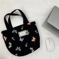 Detail of black canvas tote bag with butterfly embroidery and silver laptop on the side - Embroidered Black Butterfly