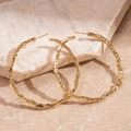 Minimalist large golden round earrings with geometric hammer texture and wavy metal finish - Hoop Earrings - Gold