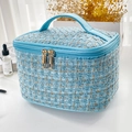Chic blue tweed makeup bag with golden double zipper and handle in a flat lay setup - Blue