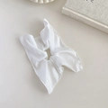 Flat lay of a white satin scrunchie next to a vintage book on a beige tabletop - Bright White