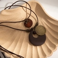 Double-layered bohemian necklace featuring wooden circles and metal bow on beige shell tray - Brown