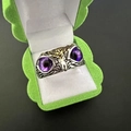 Macro detail of owl ring with purple gem eyes and gold accents in a jewelry box - Multicolor Purple