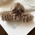 Vue détaillée d'une pince à cheveux en peluche marron posée sur un livre ouvert - Marron