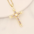 Dettaglio di un ciondolo a croce dorata con zircone viola e pietre trasparenti su ceramica - Viola