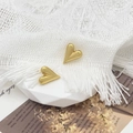 Detailed view of polished 18K gold heart studs on a white geometric display stand - Gold