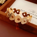 Detail of gold open bangle featuring heart cut-outs and floral texture on velvet - Gold