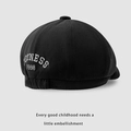 Close-up of black cotton newsboy cap with white embroidery and elastic back detail - Kids One Size / Black