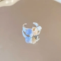 Detalle de anillo de plata con concha y cuentas azules sobre fondo reflectante - Estilo Redondo Azul Plata