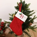 Red knitted Christmas stocking with letter B embroidery hanging on a festive tree - Letter B