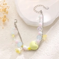 Detalle de pulsera de cuentas con dije de corazón amarillo y flores sobre piedra blanca - Cuentas Macaron Amarillas