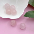 Polished 16mm pink rose quartz crystal spheres in a white flower-shaped bowl - Rose Quartz