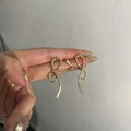 Elegant gold twisted ribbon bow earrings held in hand for a minimalist stylish look - Gold Ribbon Bow