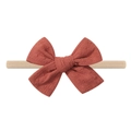 Detailed close-up of a rust-red textured bow on a soft beige elastic baby headband - Rust Red Texture (9)