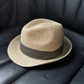 Dettaglio ravvicinato di cappello in paglia con fascia verde oliva su sedile in pelle - Stile con nastro verde