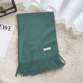 Dark green faux cashmere scarf with tassels and aesthetic label on a beige rug - Haze Blue