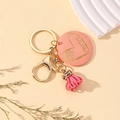 Pink wooden MAMA keychain with leather tassel and heart engraving on a warm background - Pink