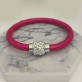 Detail eines rosenroten Silikonarmbands mit silbernem, kristallbesetztem Magnetanhänger - Rosenrot