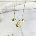 Detail van gouden schelphangers aan een kralenketting van roestvrij staal op marmer - Schelpmateriaal
