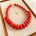 Détail d'un collier vintage rouge perlé avec des séparateurs dorés sur un plateau - Rouge