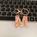 Macro detail of letter M keychain with colorful heart sequins on laptop keyboard - M