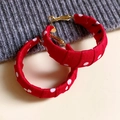 Schicke rote Polka-Dot-Stoffohrringe mit goldenen Haken auf grauem Strickhintergrund - Rot