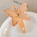 Détail de la pince papillon en acrylique abricot avec ruban rose et ressort doré - Orange