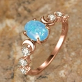 Rose gold oval opal ring with crescent moon accents and white zircons on a rock background - US 5 / Rose Gold & Blue