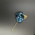 Detailed macro view of a dark blue satin rose lapel pin with a golden metal leaf decoration - Indigo Blue