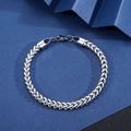 Close-up of a silver stainless steel curb link bracelet with a lobster clasp on geometric paper - Front and Back Braided Bracelet [Width 5mm] / Length 21cm