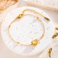 Elegant gold titanium steel heart charm bracelet on white stone tray with soft lighting - Heart Bracelet / Gold