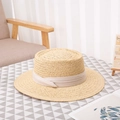 Handwoven straw boater hat with wide brim and beige ribbon band on a checkered table - Universal Size / White