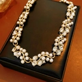 Primo piano di una collana vintage dorata con perle e cristalli su pelle nera - Collana - Oro