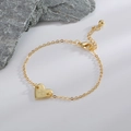 Bracelet coeur doré avec gravure lettre X et fermoir mousqueton sur fond minimaliste - Lettre X