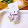 Detail of two purple grape cartoon hair ties on display card with warm floral background - Grape Hair Ties Pair