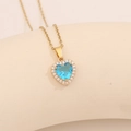 Nahaufnahme der goldenen Herz-Halskette mit blauem Edelstein und Zirkonia-Verzierung - See Blau