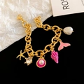 Gouden schakelarmband met bedels van zeesterren, schelpen en vissenstaarten in roze - Paarse Zeester Wulk Armband