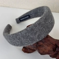 Detailed shot of grey wool headband with handmade label on natural wood texture - Gray