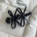 Detail view of a vintage black glossy double bow hair clip with silver metal spring fastener - Black