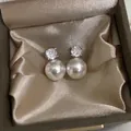 Elegante silberne Perlenohrringe mit Zirkonia-Steckern auf Satin-Hintergrund - Silber Krallenfassung Zirkon Perle Ohrstecker (E6806)