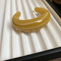 Detail of amber acrylic C-shaped cuff bracelet with smooth polished resin finish - Amber Yellow