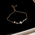 Vista macro di un bracciale dorato regolabile con stella, luna e zirconi brillanti - Bracciale-Oro-Stella