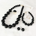 Flat lay of vintage black pearl necklace set with matching bracelet and earrings - Black