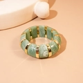 Macro view of green marble texture acrylic segments with gold metal spacers on a bracelet - Green