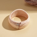 Dettaglio macro di un ampio bracciale in resina con trama marmorea rosa e lucida - Beige Irregolare