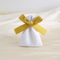 Detailed view of a white velvet drawstring gift bag with a gold ribbon bow on beige fabric - 7*9cm / White with Gold Ribbon