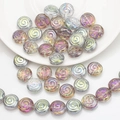Gros plan de perles rondes en verre à spirale colorées sur une assiette en céramique - Rose Rouge Vert